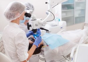 Dental professionals performing a procedure using a dental microscope in a clinic